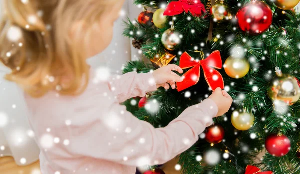 Nahaufnahme eines kleinen Mädchens, das den Weihnachtsbaum schmückt — Stockfoto