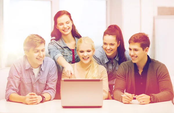 Lachende studenten kijken naar laptop op school — Stockfoto