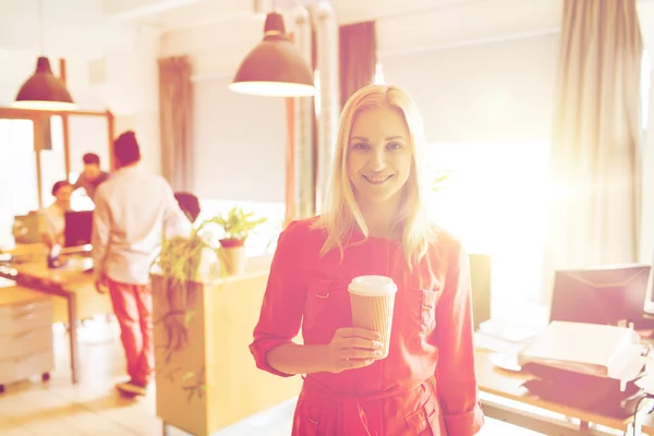 Femme créative heureuse avec tasse de café au bureau — Photo