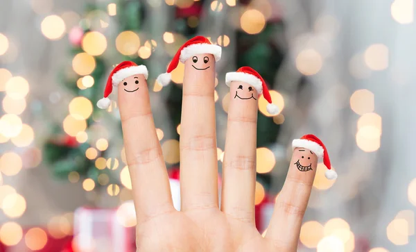 Primer plano de la mano con cuatro dedos en sombreros de santa —  Fotos de Stock