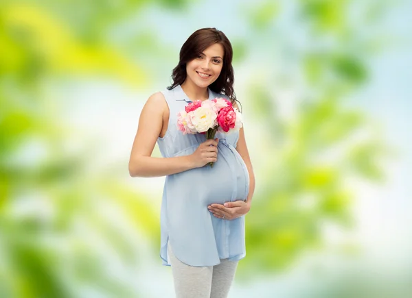 Felice donna incinta con fiori che toccano la pancia — Foto Stock