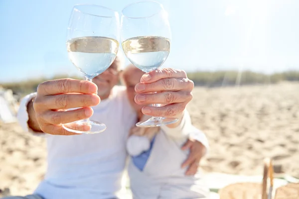 Счастливая пожилая пара пьет вино на летнем пляже — стоковое фото