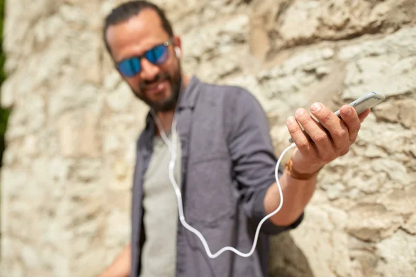 Man with earphones and smartphone on street — Stock Photo, Image