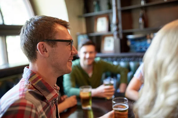 Счастливый человек пьет пиво с друзьями в баре или пабе — стоковое фото