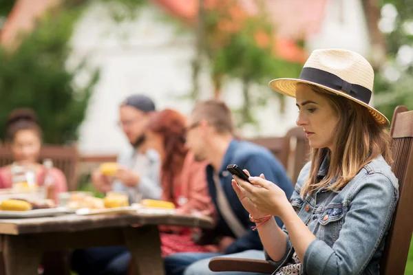 Vrouw met smartphone en vrienden op zomer feest — Stockfoto