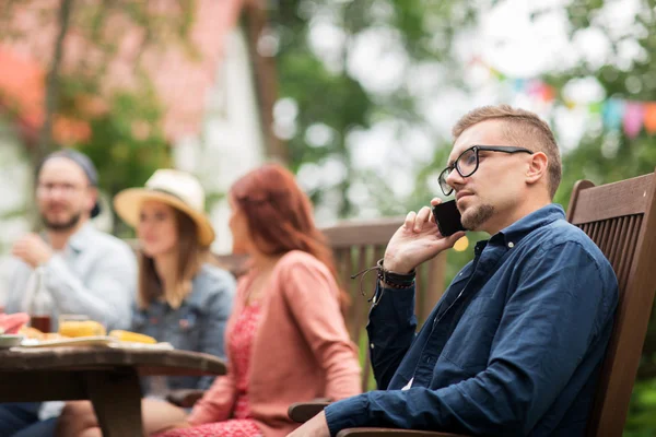 Man with smartphone and friends at summer party — Stock Photo, Image