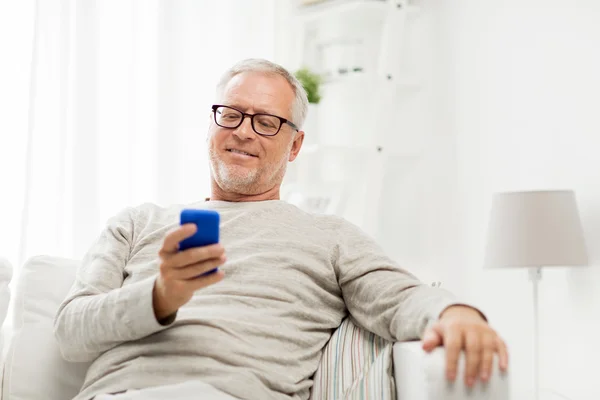 Homem sênior feliz mensagens de texto no smartphone em casa — Fotografia de Stock