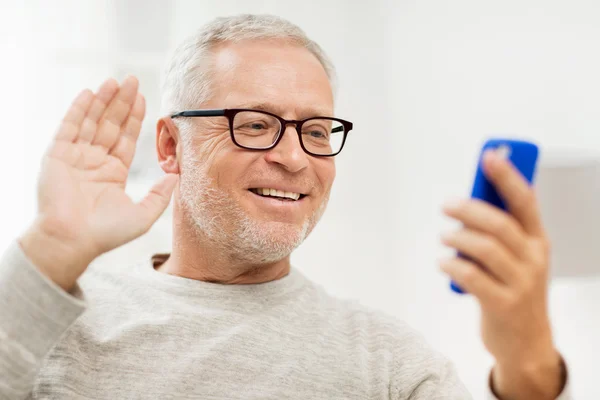 Senior man having video call on smartphone at home — Stock Photo, Image