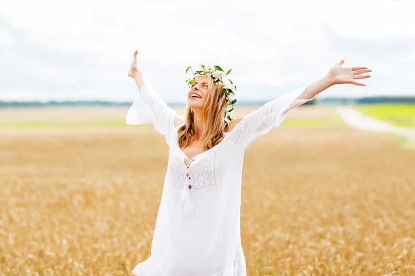 Happy young woman in flower wreath on cereal field Stock Photo