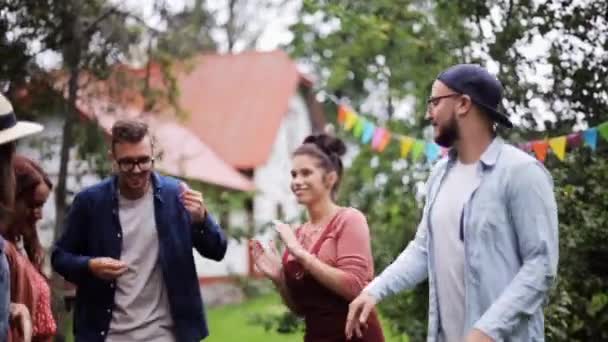 Счастливые друзья танцуют на летней вечеринке в саду — стоковое видео