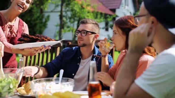 Счастливые друзья, ужинающие на вечеринке в летнем саду — стоковое видео