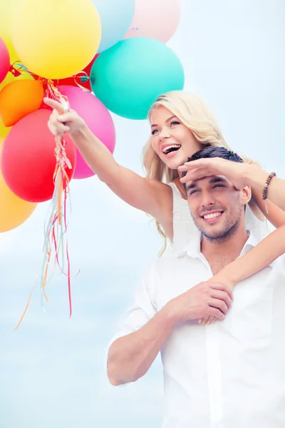 Paar mit bunten Luftballons am Meer — Stockfoto