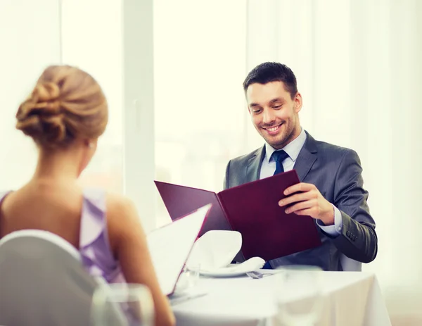 Lächelnder junger Mann beim Blick auf Speisekarte im Restaurant — Stockfoto