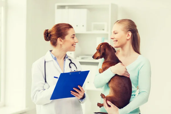 Femme heureuse avec chien et médecin à la clinique vétérinaire — Photo