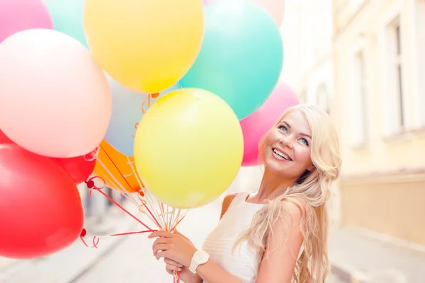 Улыбающаяся женщина с цветными воздушными шарами — стоковое фото