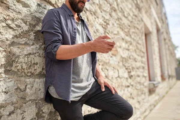 Primer plano del hombre con teléfono inteligente en la pared de piedra — Foto de Stock