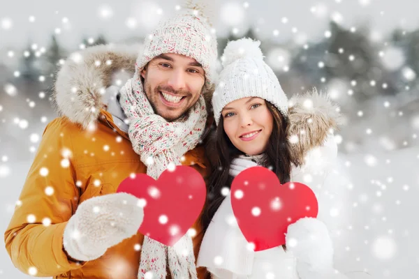 Casal feliz com corações vermelhos sobre paisagem de inverno — Fotografia de Stock