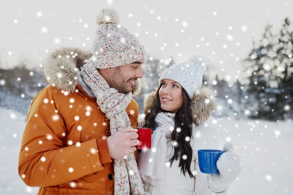 Feliz pareja con tazas de té sobre el paisaje de invierno —  Fotos de Stock