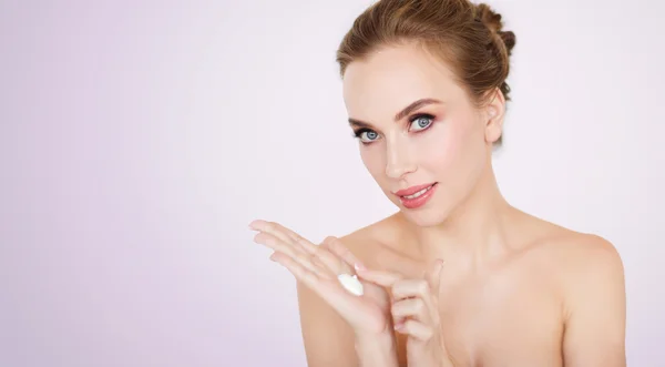 Happy young woman with moisturizing cream on hand — Stock Photo, Image