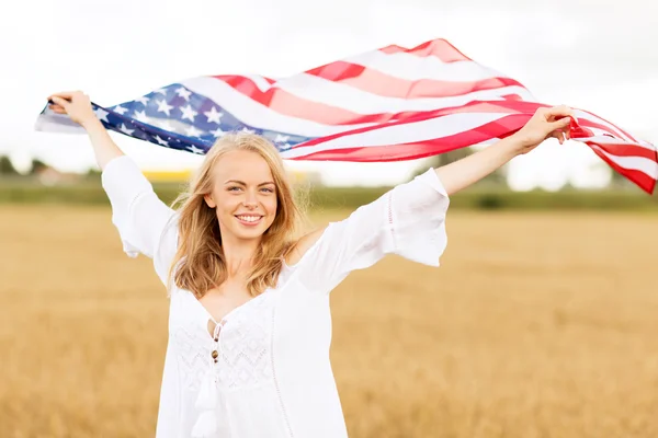 Šťastná žena s americkou vlajkou na obilném poli — Stock fotografie