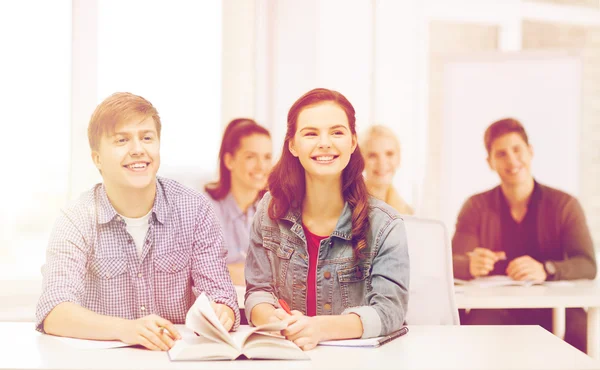 Two teenagers with notebooks and book at school — Stock Photo, Image