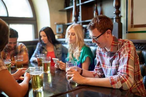 Přátelé se smartphony a pivo v baru nebo v hospodě — Stock fotografie