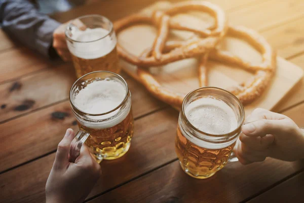 Close up de mãos com canecas de cerveja no bar ou pub — Fotografia de Stock