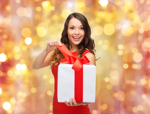 Mulher sorridente em vestido vermelho com presente de Natal — Fotografia de Stock