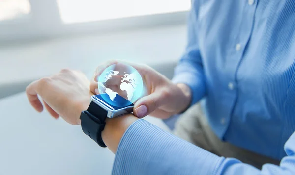 Close up of hands and globe hologram on smartwatch — Stock Photo, Image