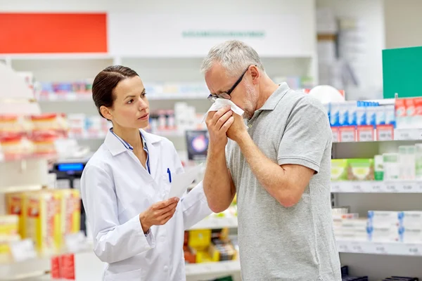 Apotheker en senior man met griep bij apotheek — Stockfoto