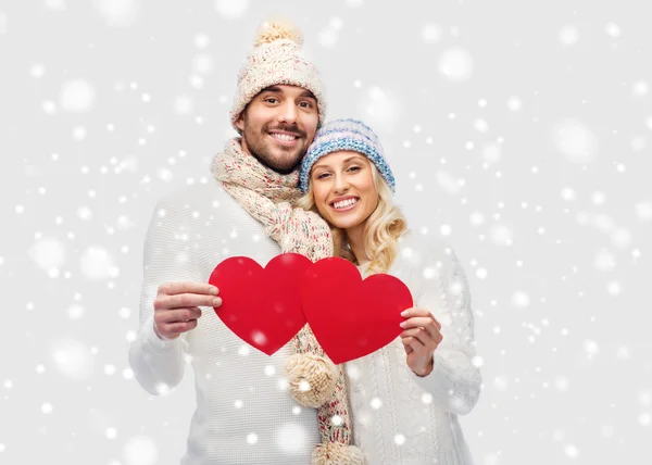 Lächelndes Paar in Winterkleidung mit roten Herzen — Stockfoto