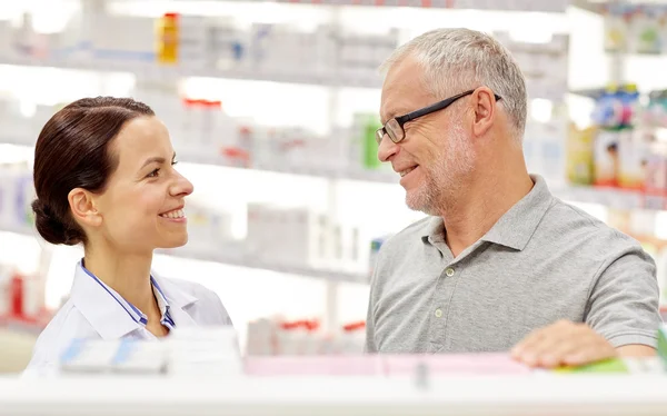 Farmacêutico feliz falando com o homem sênior na farmácia — Fotografia de Stock