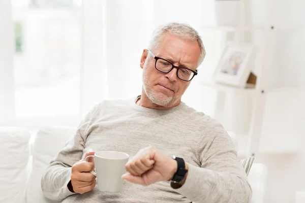 Seniorchef mit Kaffee schaut auf Armbanduhr — Stockfoto