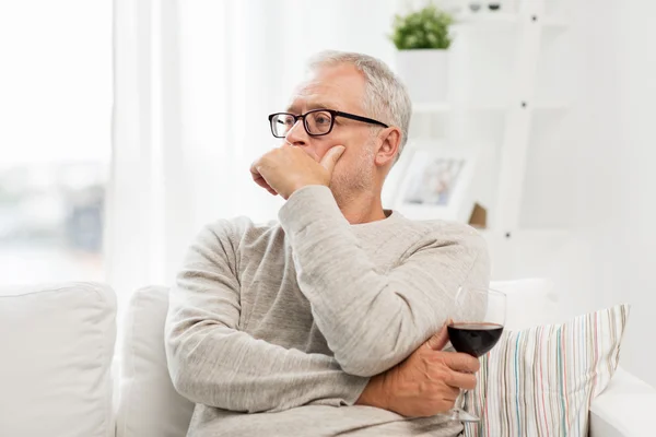 Starší muž pít červené víno ze skla doma — Stock fotografie