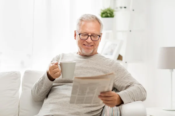 Hombre mayor en gafas leyendo el periódico en casa — Foto de Stock