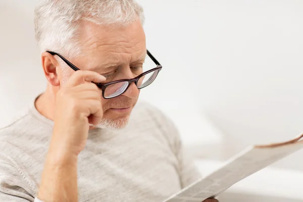 Close up of old man in glasses reading newspaper — Stock Photo, Image