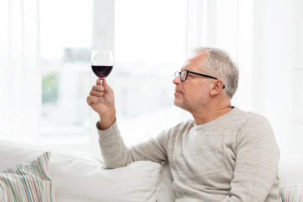 Ανώτερος άνθρωπος πόσιμο κόκκινο κρασί από το γυαλί στο σπίτι — Φωτογραφία Αρχείου