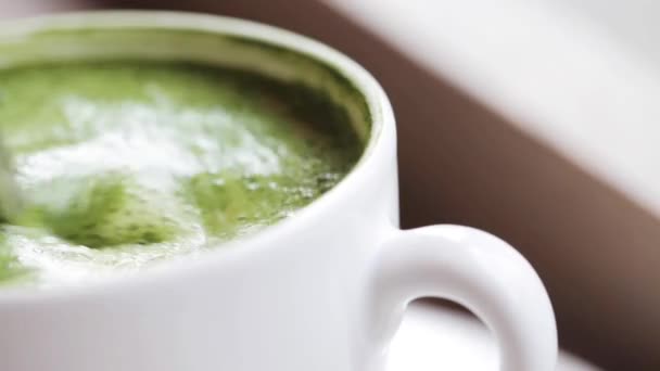 Teaspoon stirring matcha green tea latte in cup — Stock Video