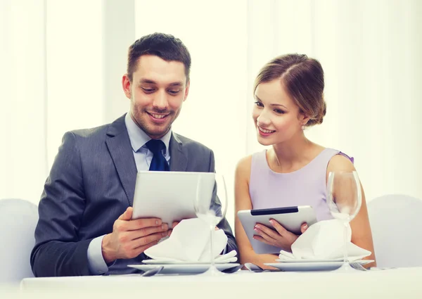 Pareja con menús en la tableta PC en el restaurante —  Fotos de Stock