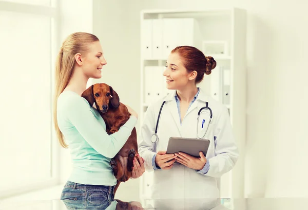 Happy woman with dog and doctor at vet clinic — Stock Photo, Image