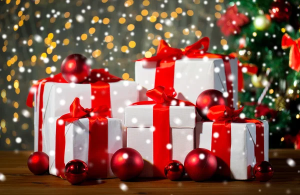Geschenkdozen en rode ballen onder kerstboom — Stockfoto