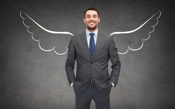 Šťastný podnikatel s andělskými křídly nad šedá — Stock fotografie