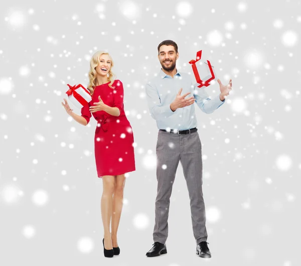 Gelukkige paar met kerst geschenkdozen over sneeuw — Stockfoto