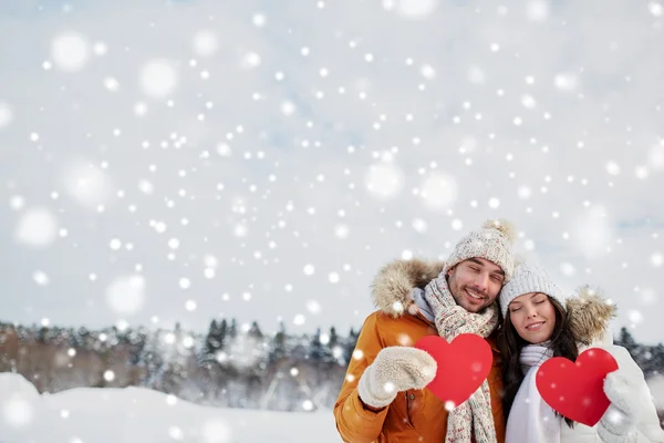 Casal feliz com corações vermelhos sobre paisagem de inverno — Fotografia de Stock