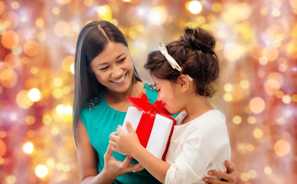 Happy mother and girl with gift box over lights — Stock Photo, Image