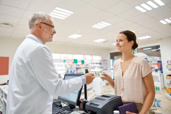Mujer dando dinero al farmacéutico en la farmacia — Foto de Stock