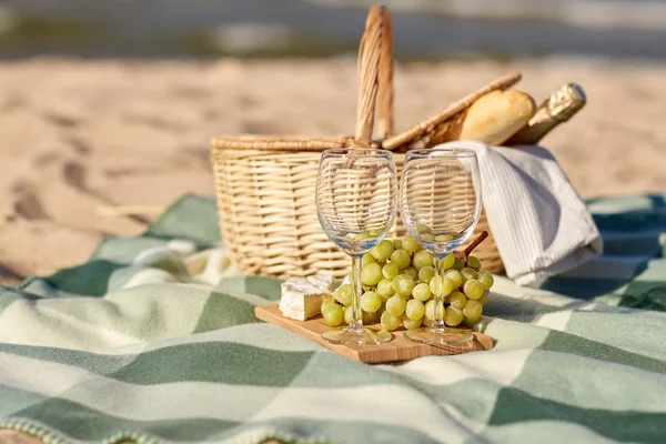 Cesta de piquenique com copos de vinho e comida na praia — Fotografia de Stock