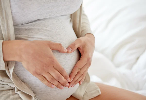 Närbild av gravid kvinna gör hjärtat gest — Stockfoto