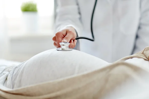 Médico con estetoscopio y mujer embarazada — Foto de Stock