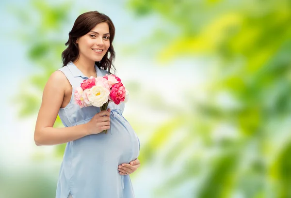 Ευτυχισμένος έγκυος γυναίκα με λουλούδια που αγγίζουν την κοιλιά — Φωτογραφία Αρχείου
